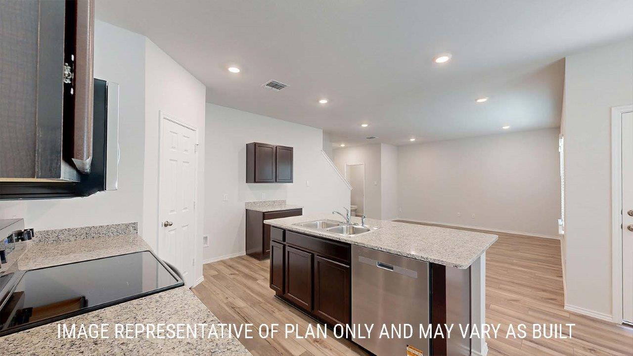 Emma kitchen with dark cabinets and granite countertops and view of living room.