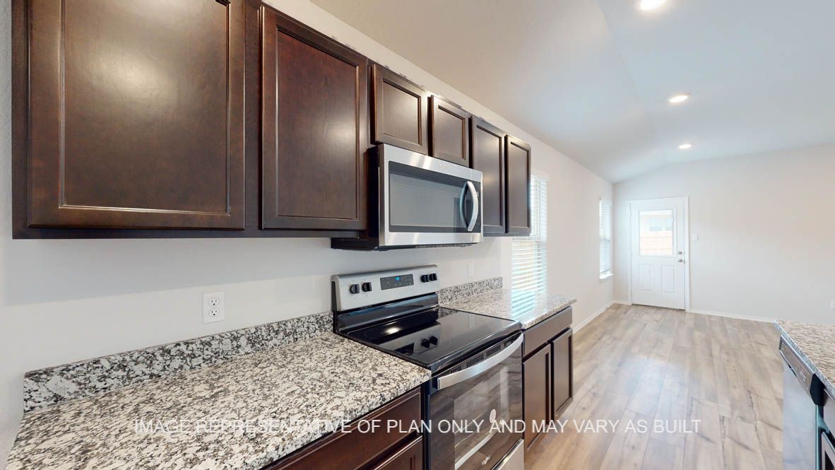 Abbot kitchen with granite island, dark cabinets and stainless appliances.