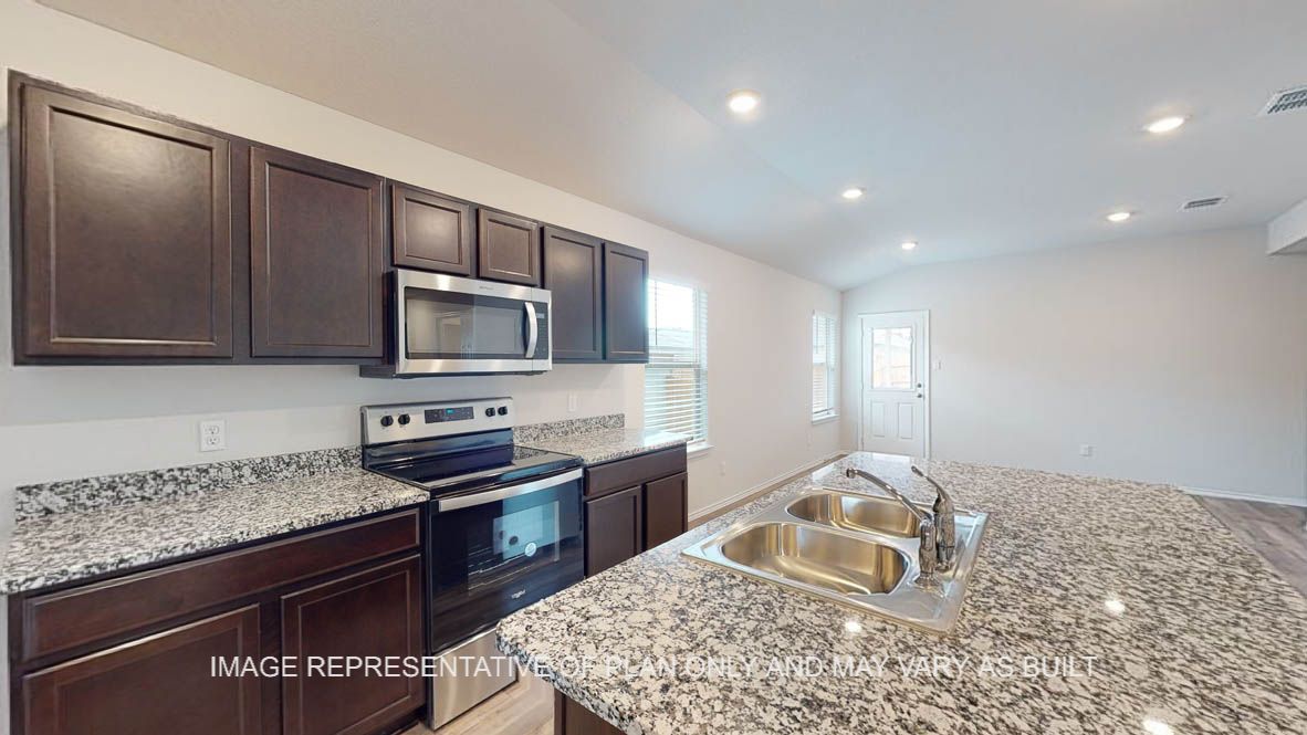 Abbot kitchen with granite island, dark cabinets and stainless appliances.