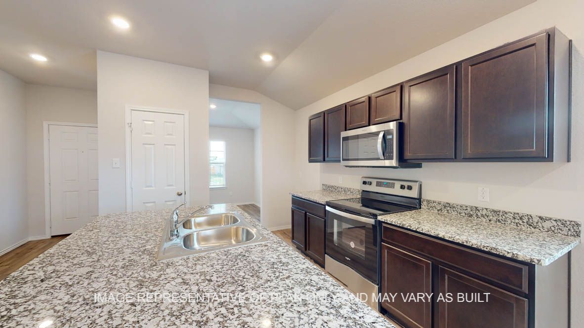 Abbot kitchen with granite island, dark cabinets and stainless appliances.
