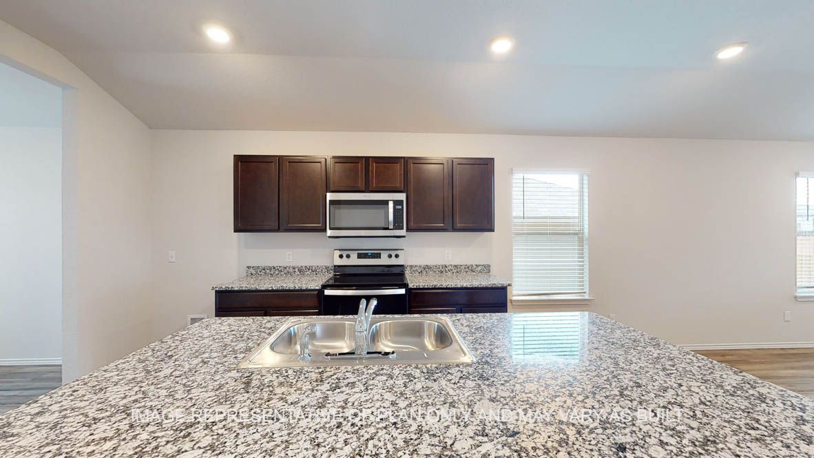 Abbot kitchen with granite island, dark cabinets and stainless appliances.