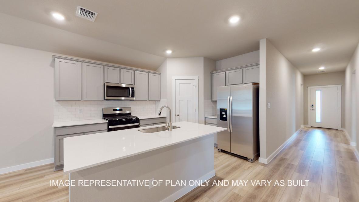 Easton kitchen with view to entry, quartz kitchen island, gray cabinets and vinyl plank flooring.