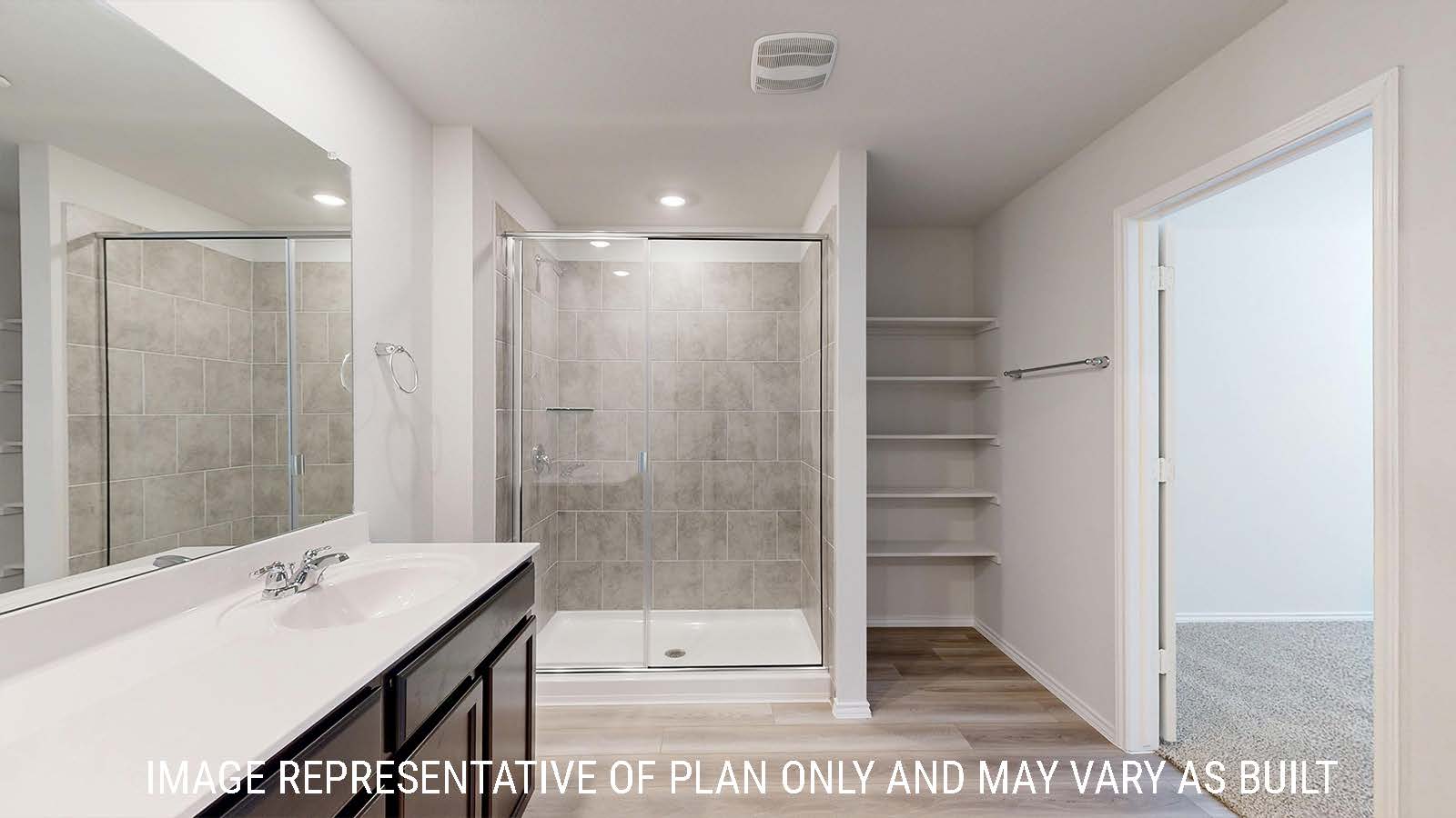 Gaven primary bathroom with white vanity counter and walk-in shower and shelving for storage.