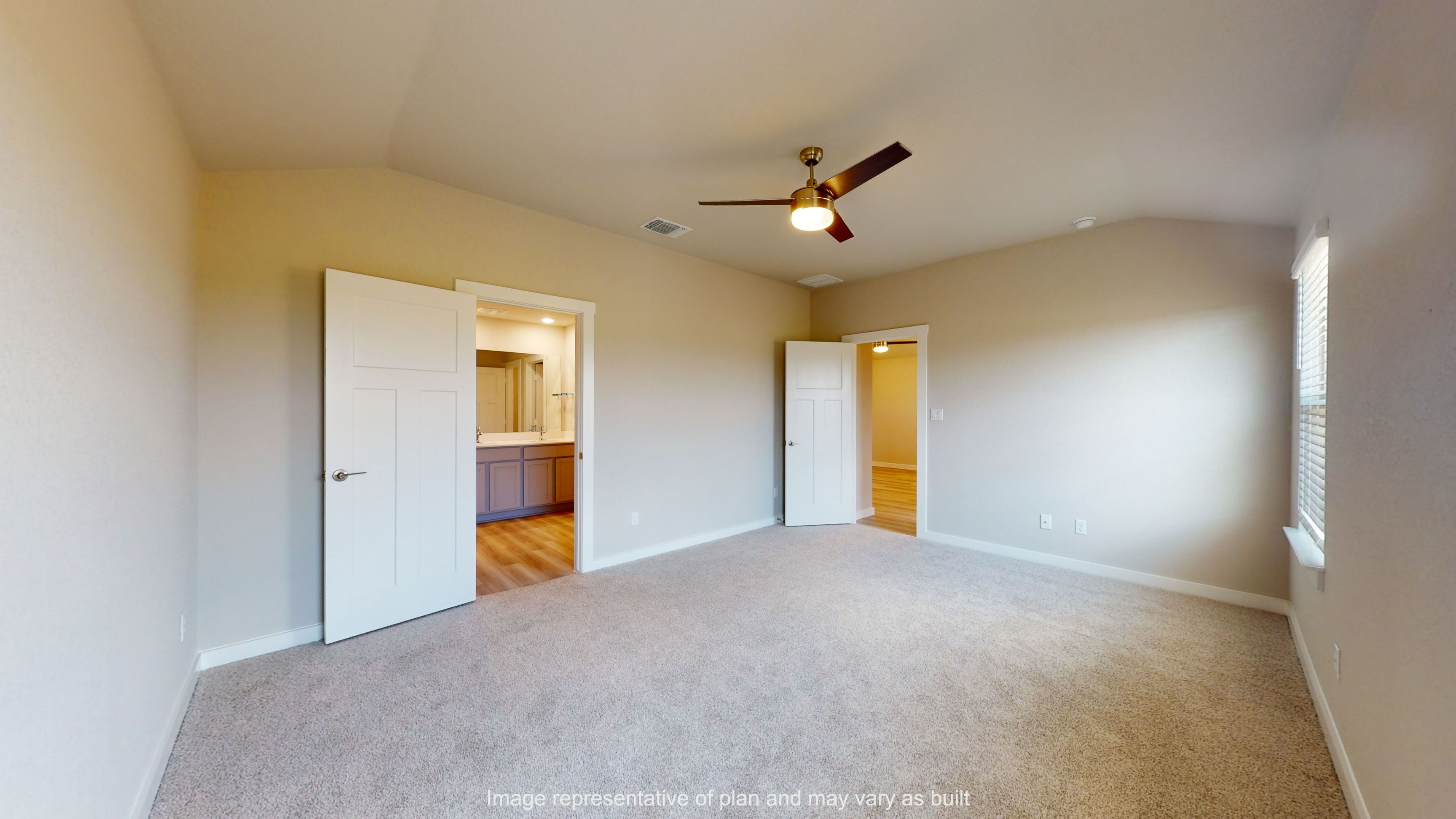 Gaven primary bedroom with carpet flooring and entry into primary bathroom.