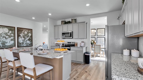 Turnbo Ranch Traditions model home kitchen with granite tops and gray cabinets.
