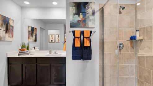 Oak Ridge model home primary bath with dark cabinets and white countertops.