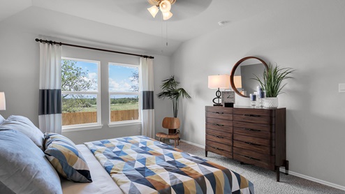 Oak Ridge model home primary bedroom with king sized bed and windows.