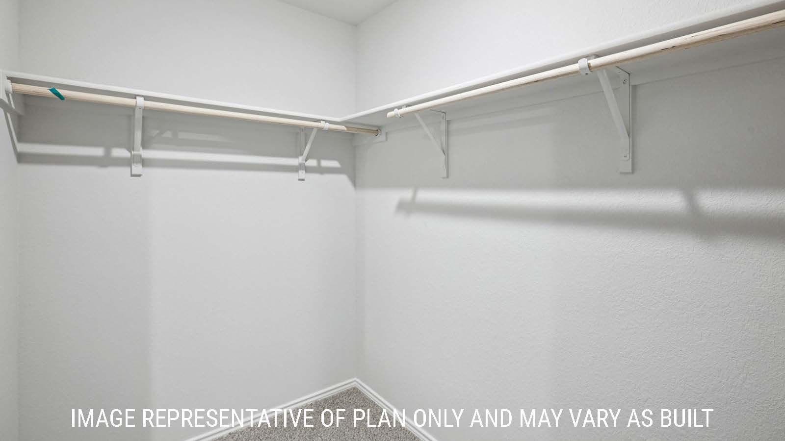 Barton primary bedroom closet with carpeted flooring and shelving for storage.