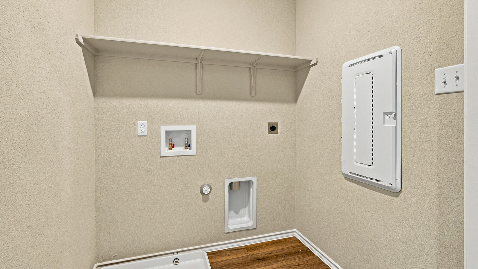 Pepper Creek Crossing model utility room with washer and dryer connections and shelving for storage.