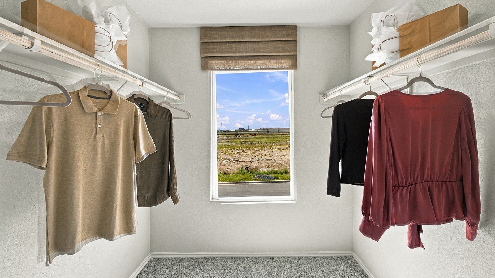 Pepper Creek Crossing model primary bedroom closet with carpeted flooring and window for natural lighting.