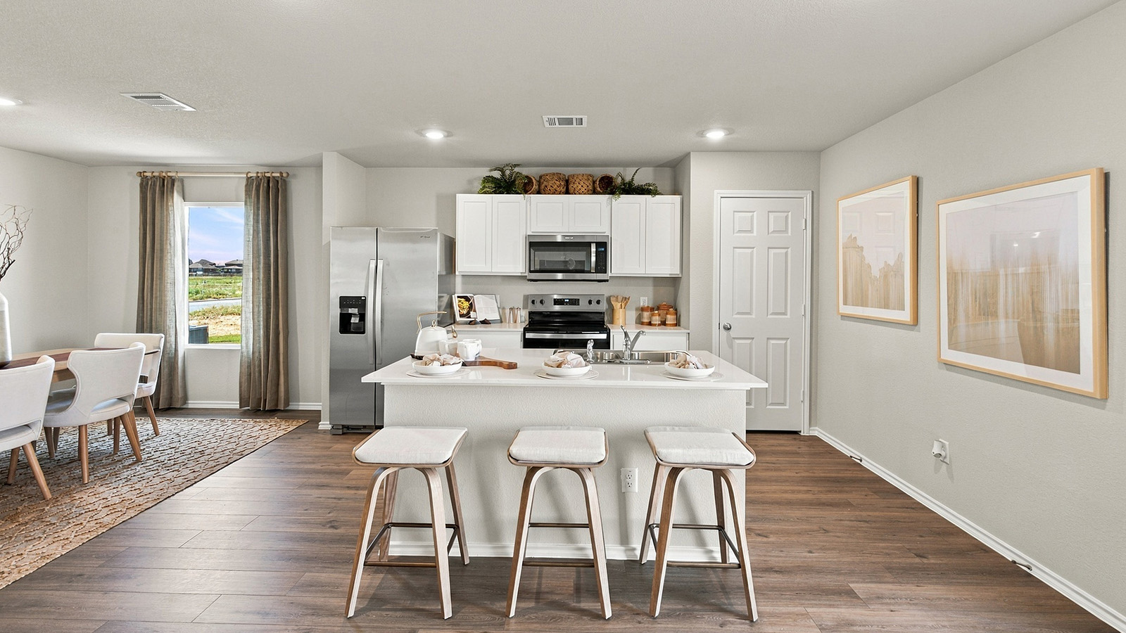 Pepper Creek Crossing model kitchen with kitchen island with light cabinets and view of open concept dining room.