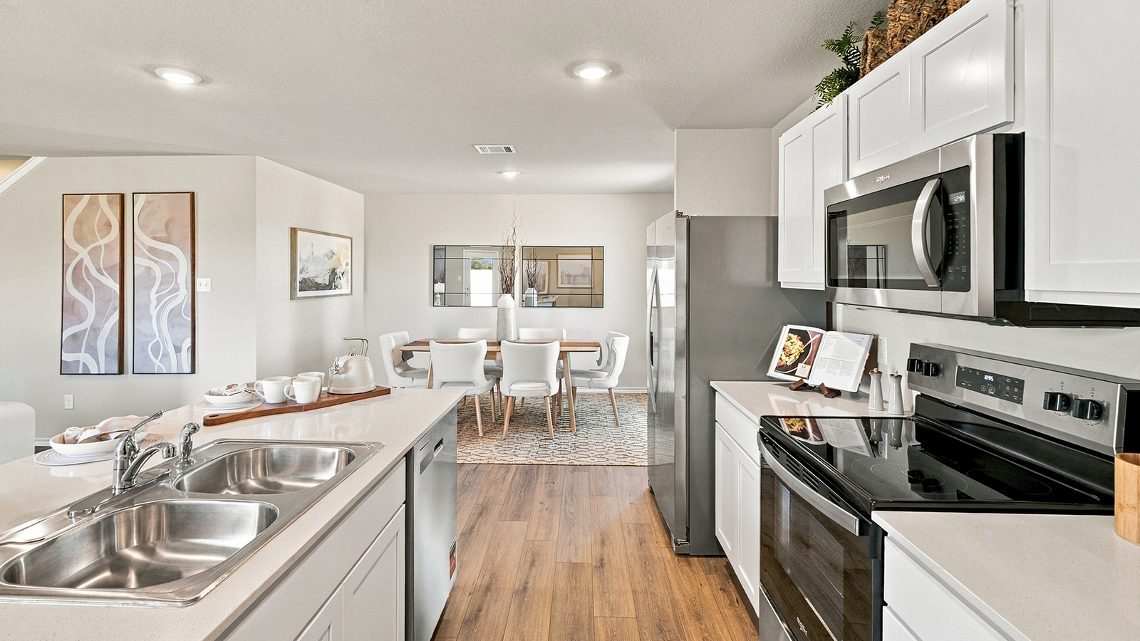Pepper Creek Crossing model kitchen with light cabinets and granite countertops with view of open concept dining room.