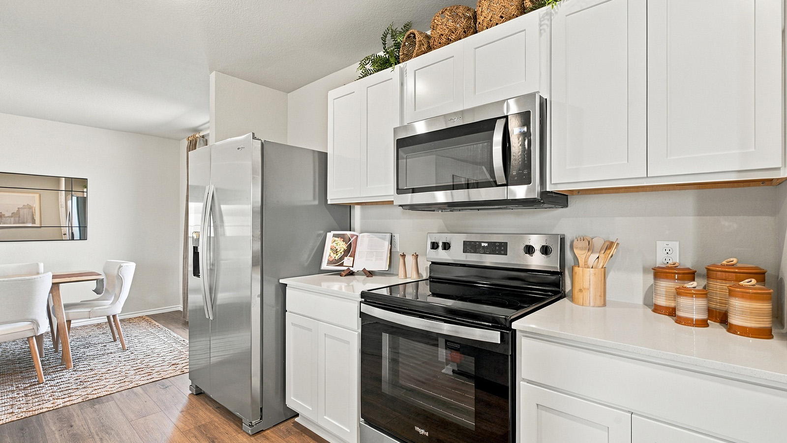 Pepper Creek Crossing model kitchen with light cabinets and granite countertops with view of open concept dining room.
