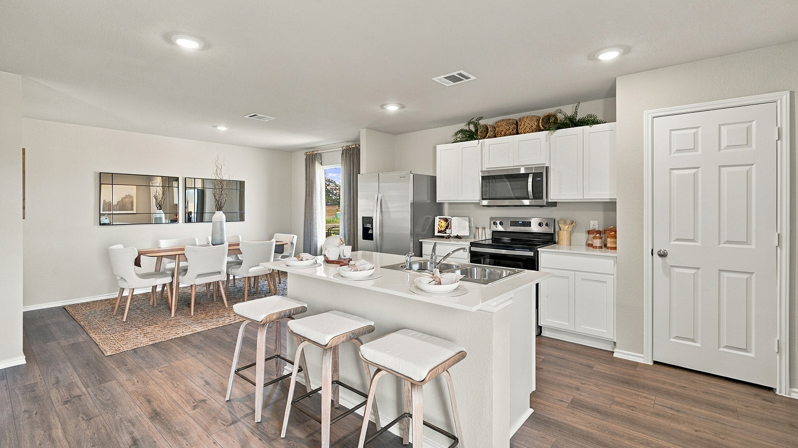 Pepper Creek Crossing model kitchen with kitchen island with white cabinets and view of open concept dining room.