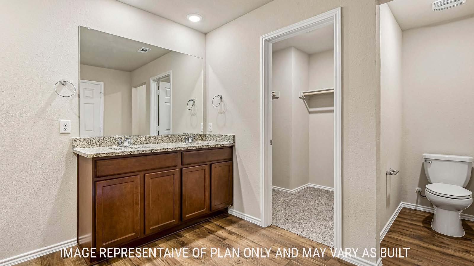 Prosper primary bathroom with double vanity and view of primary walk-in closet.