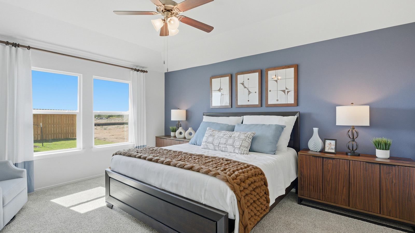 Eagles Landing Model Home primary bedroom with king size bed and carpeted flooring with windows for lighitng.