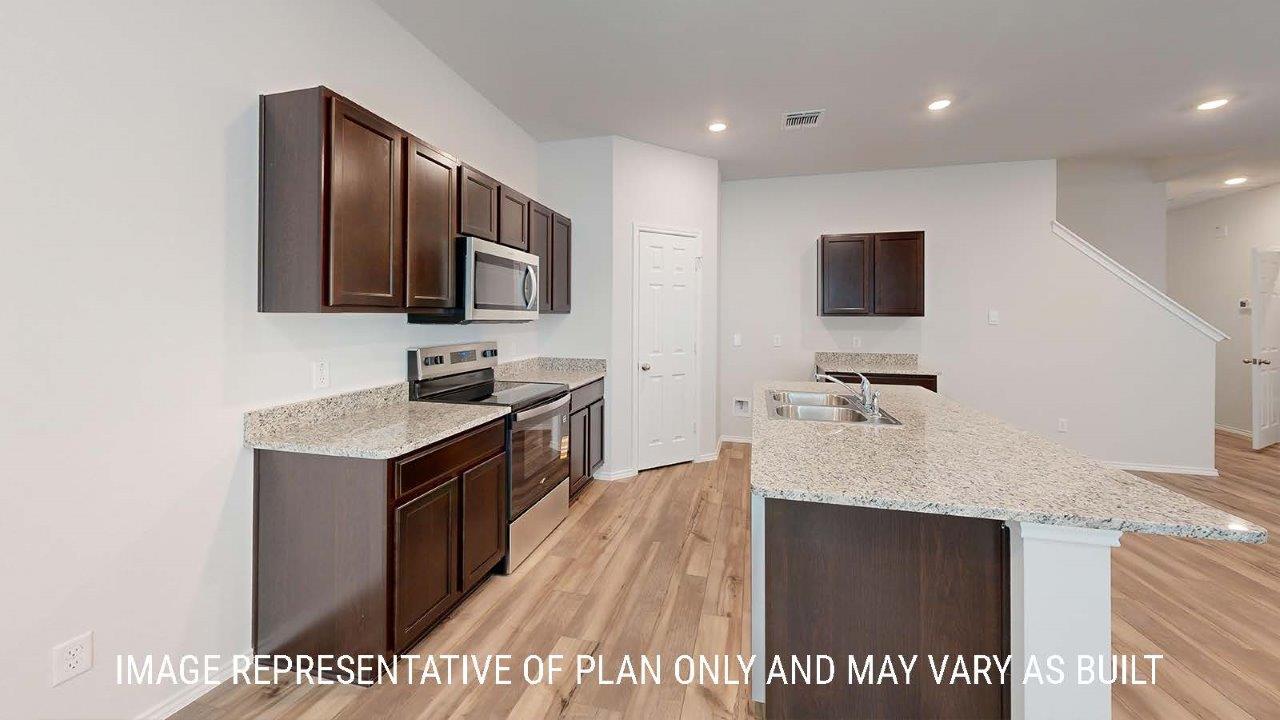 Emma kitchen with dark cabinets and granite countertops.