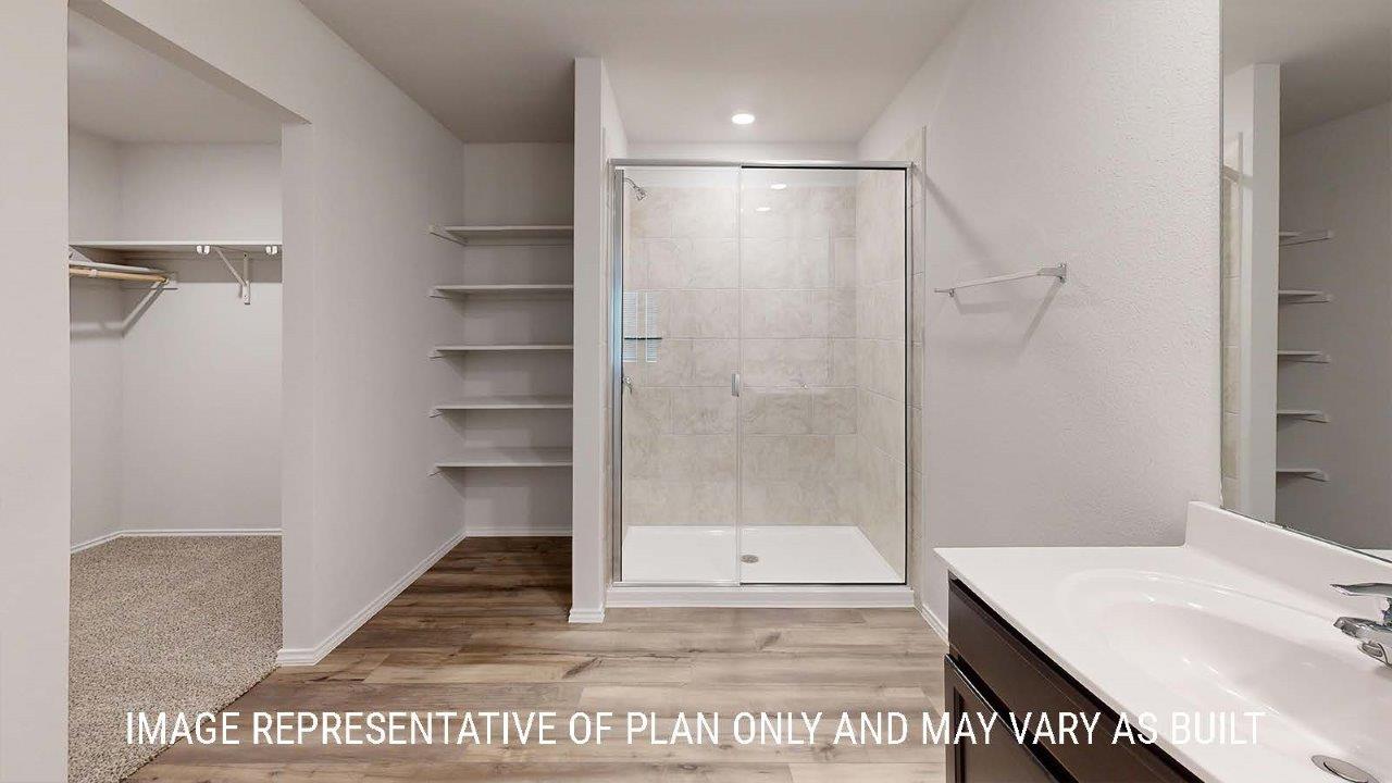 Emma primary bathroom with walk-in shower and view of primary walk-in closet.
