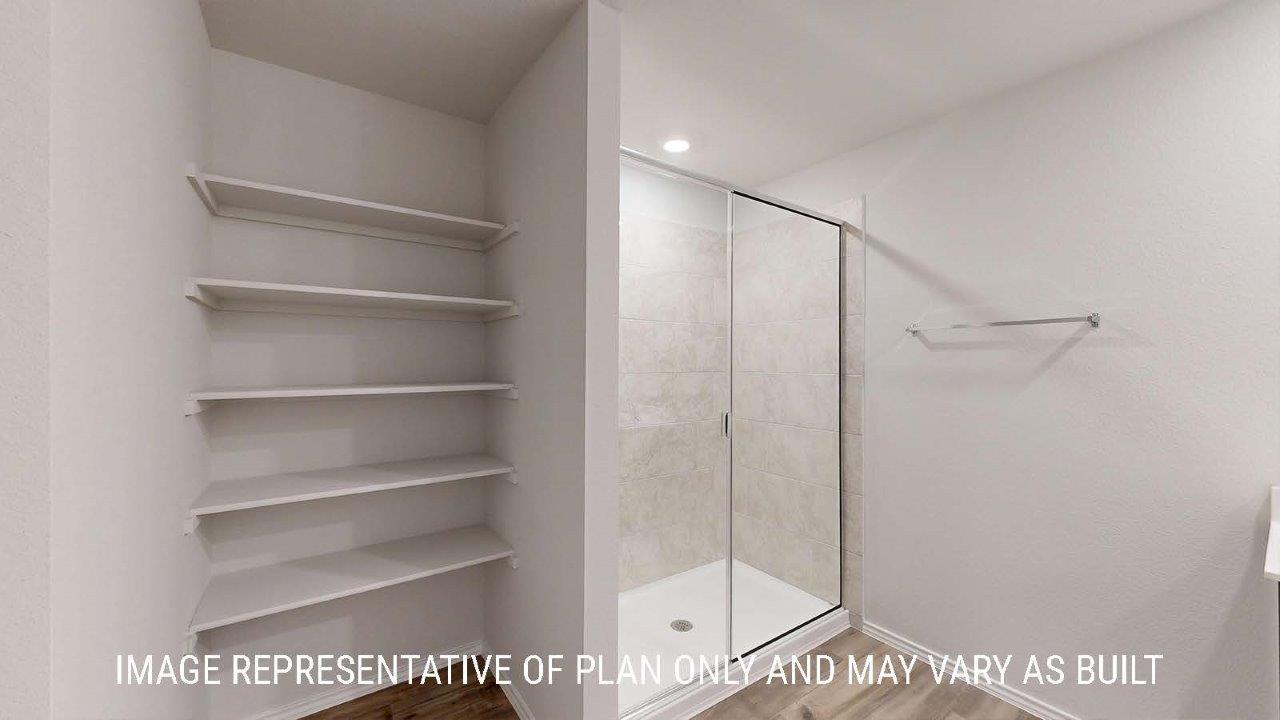 Emma primary bathroom with walk-in shower and shelving for storage.