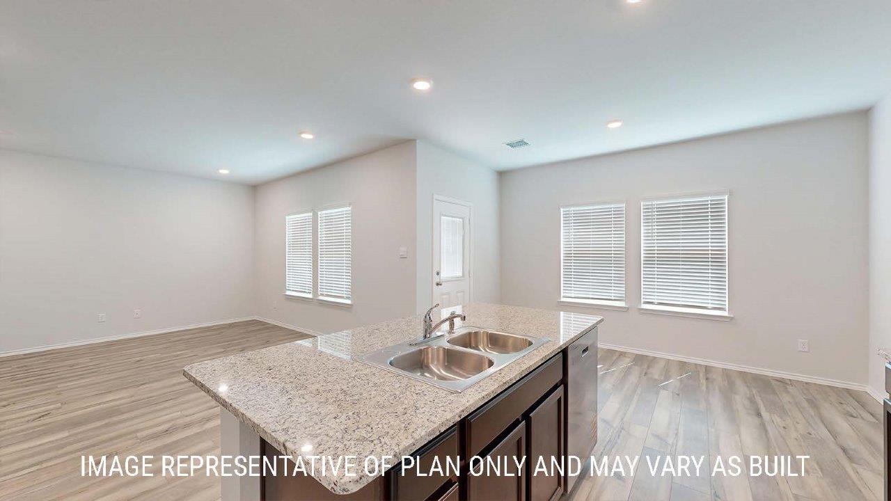 Emma kitchen with center kitchn island with granite countertops and view of open concept living room and dining room.