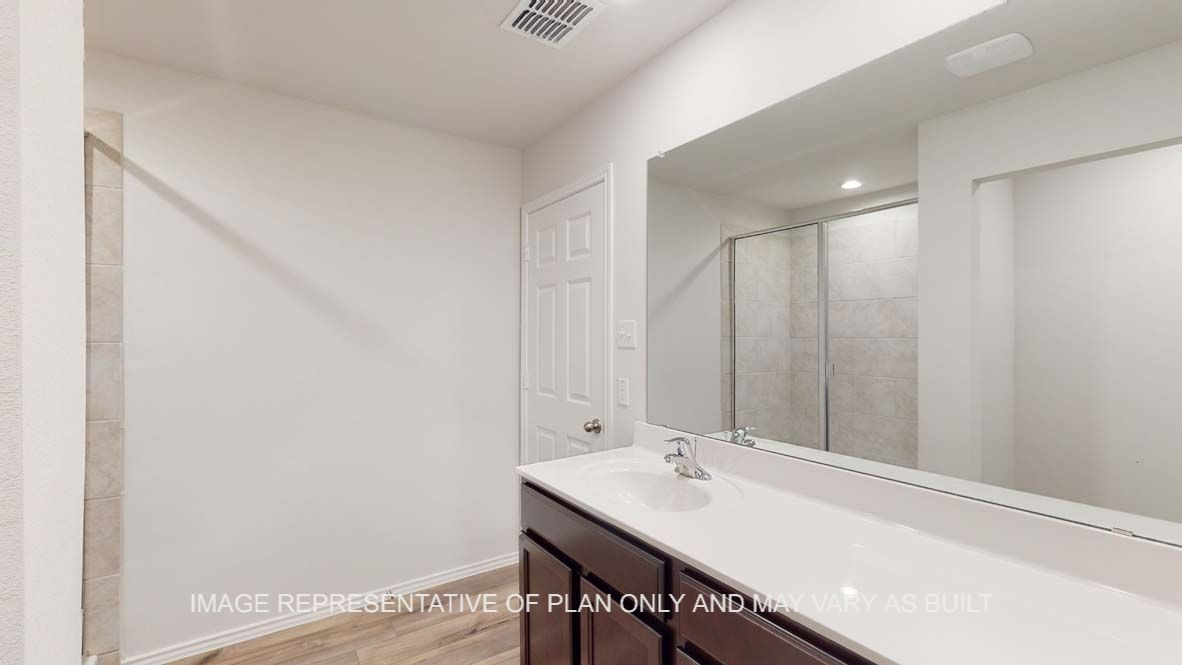 Ashburn primary bathroom with dark cabinets and white countertops.