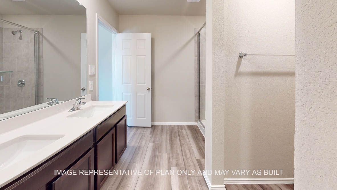 Elgin primary bathroom with vinyl plank flooring and dark cabinets and white countertops.