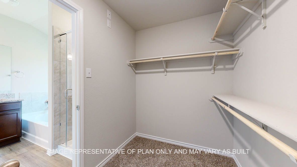 Richmond primary walk-in closet with carpet flooring.