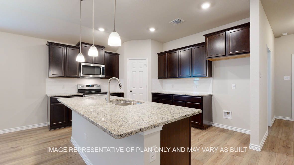 Richmond kitchen with center island and undermount sink with pendants lights above island.