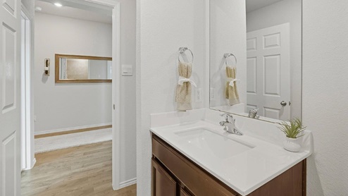 Mesa Ridge model home secondary bathroom with single vanity sink and brown cabinets.