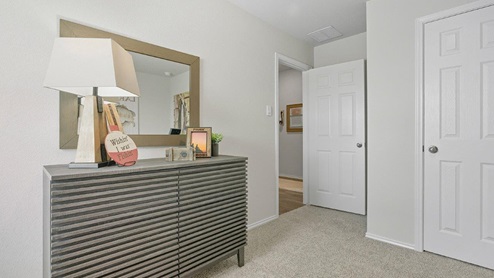 Mesa Ridge model home secondary bedroom with carpeted flooring and closet door.