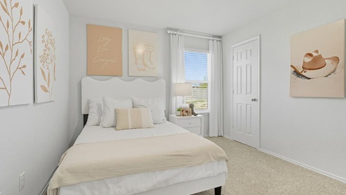 Mesa Ridge model home secondary bedroom with carpeted flooring and window for lighting.