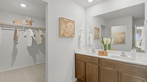 Mesa Ridge model home primary bathroom with double vanity sink and view of primary walk-in closet.