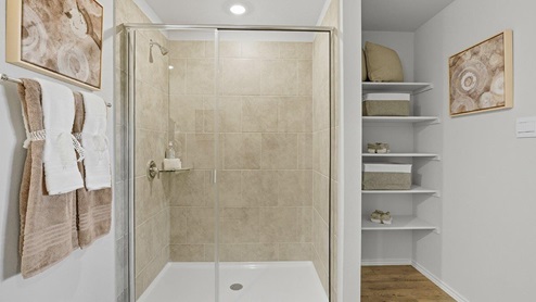 Mesa Ridge model home primary bathroom with walk-in shower and shelving for storage.