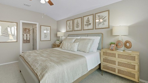 Mesa Ridge model home primary bedroom with carpeted flooring and view of primary bathroom.