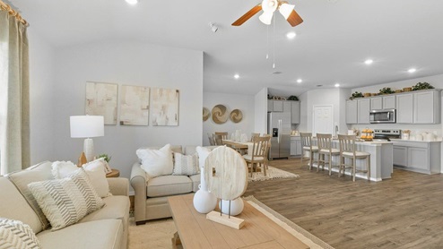 Mesa Ridge model home living room with view of open concept dining room and kitchen.