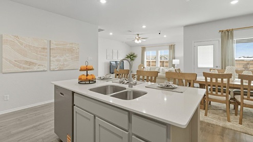 Mesa Ridge model home kitchen with center kitchen island and view of open concept dining room and living room.