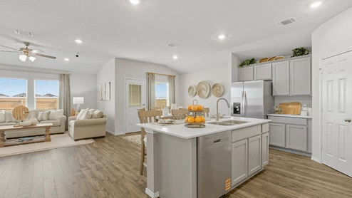 Mesa Ridge model home kitchen with center kitchen island and view of open concept dining room and living room.
