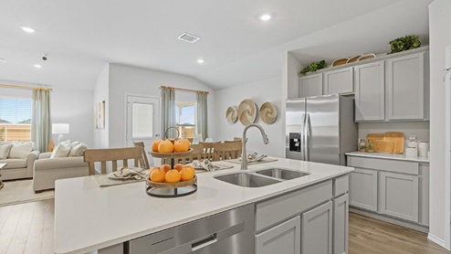 Mesa Ridge model home kitchen with center kitchen island and view of open concept dining room and living room.