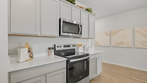 Mesa Ridge model home kitchen with light grey cabinets and granite countertops.