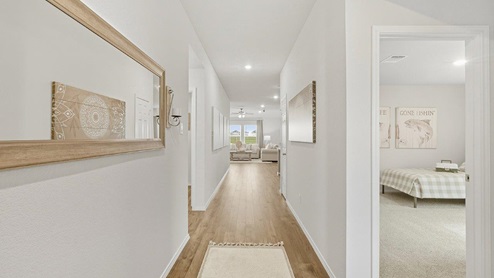 Mesa Ridge model home entry with vinyl flooring and view of living room and secondary bedroom.