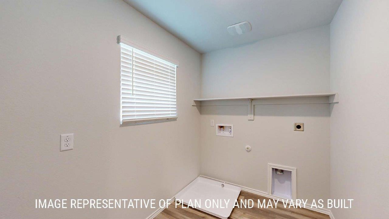 Emma utility room with washer and dryer connections and shelving for storage.