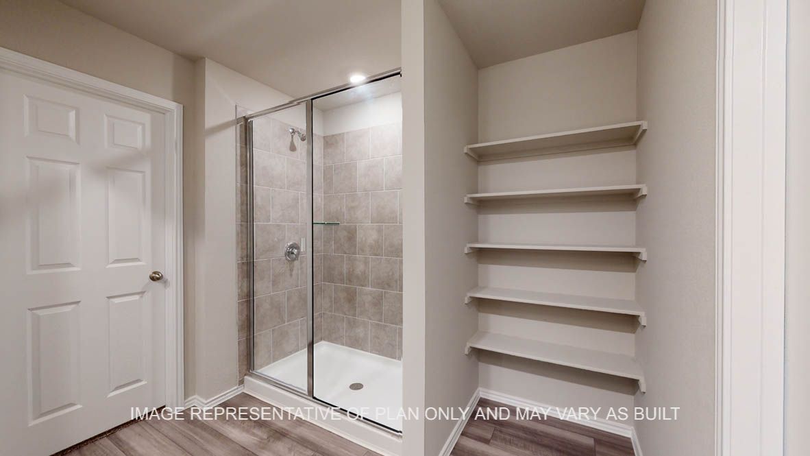 Fargo primary bath with walk-in shower with ceramic tile surround and open shelving.