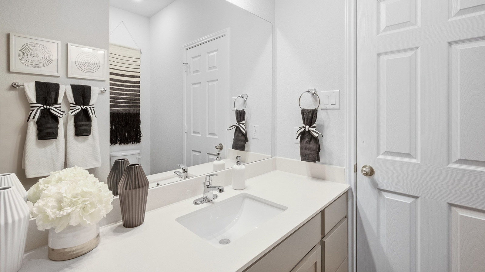 Homestead Model secondary bathroom with vanity sink and grey cabinets and granite countertops.