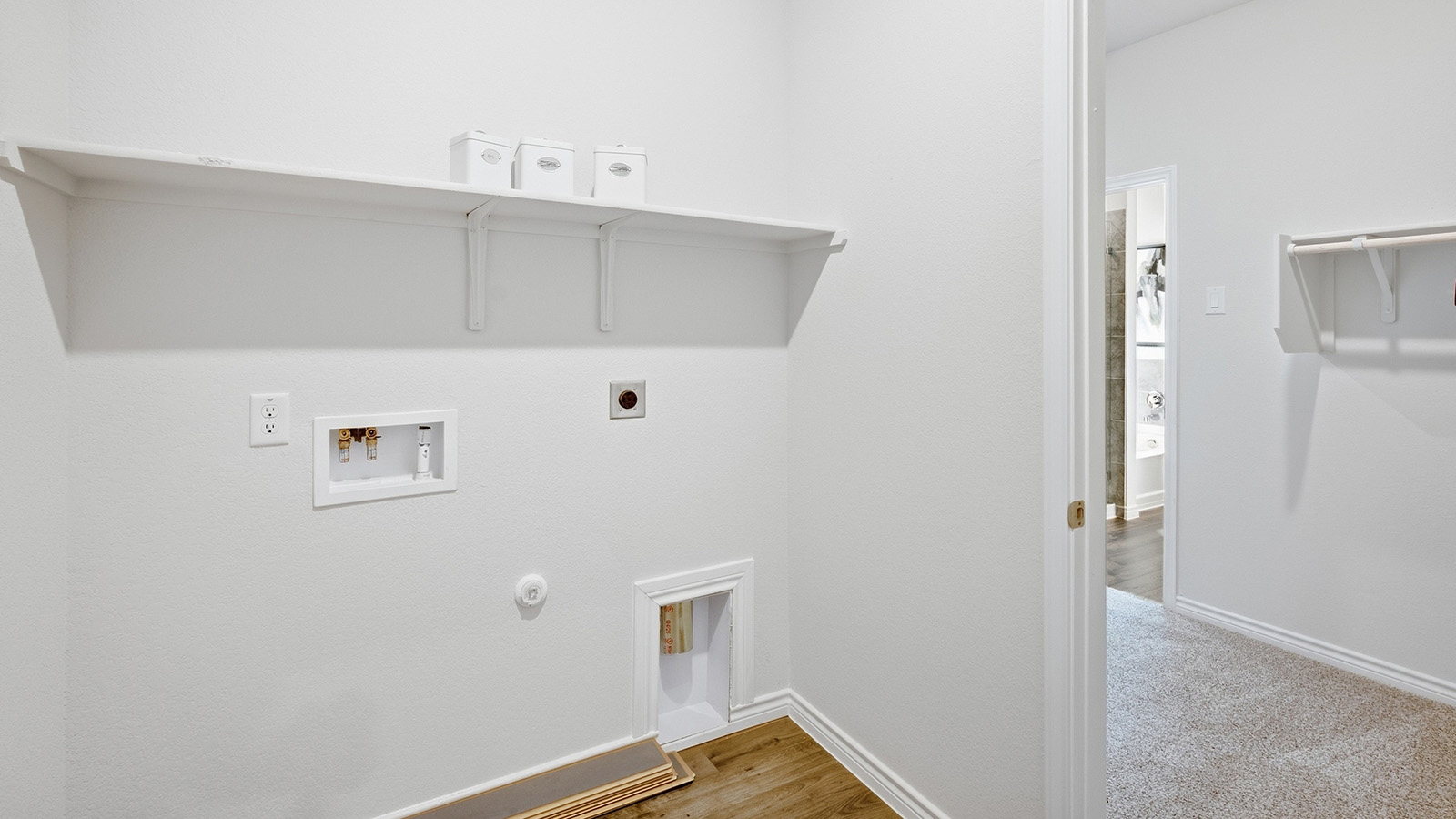 Homestead Model utility room with washer and dryer connections and shelving for storage.