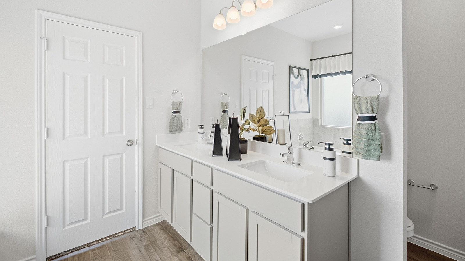 Homestead Model primary bathroom with double vanity sink and white cabinets and granite countertops.