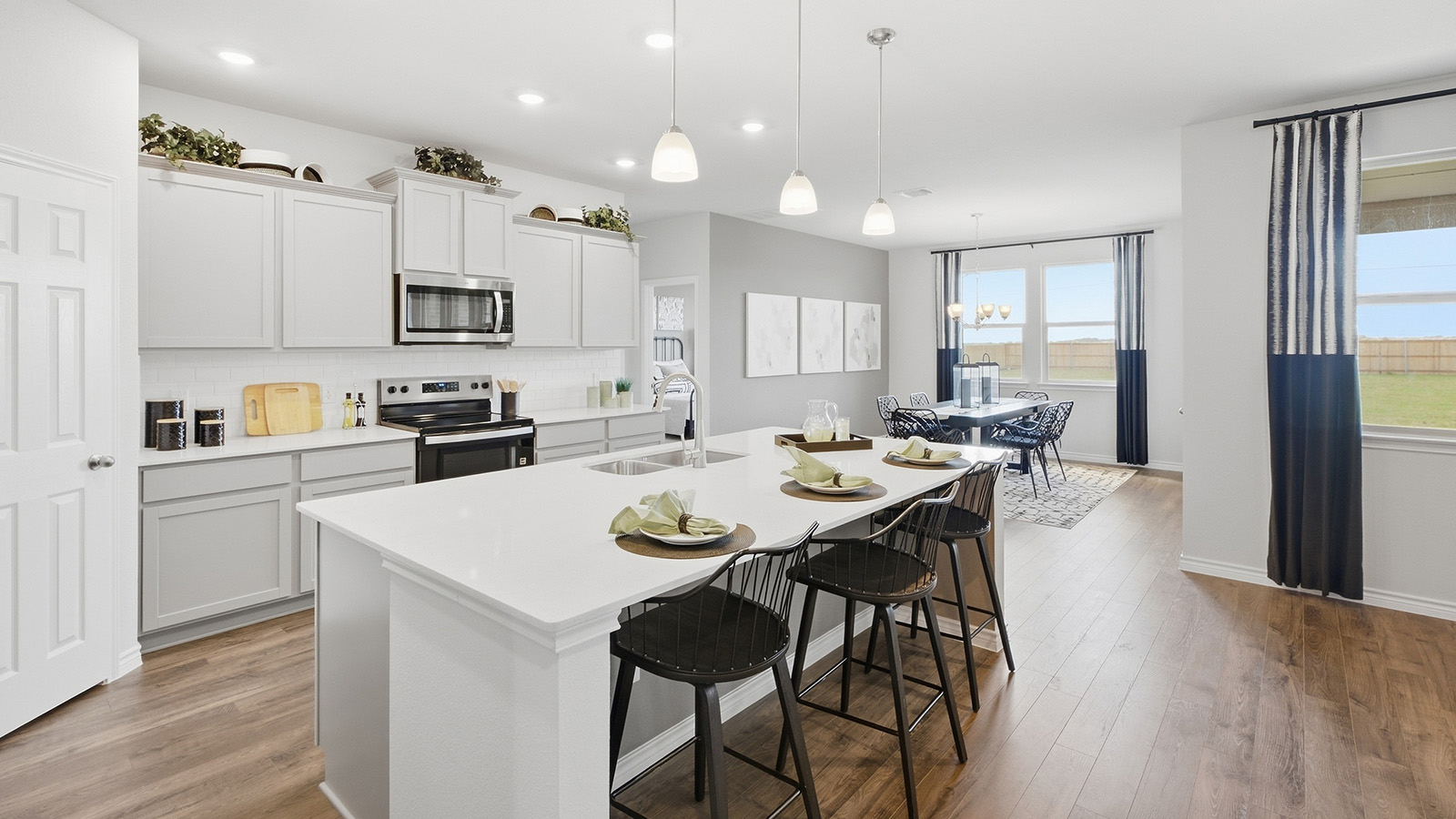 Homestead Model  kitchen with kitchen island with light cabinets and granite countertops.