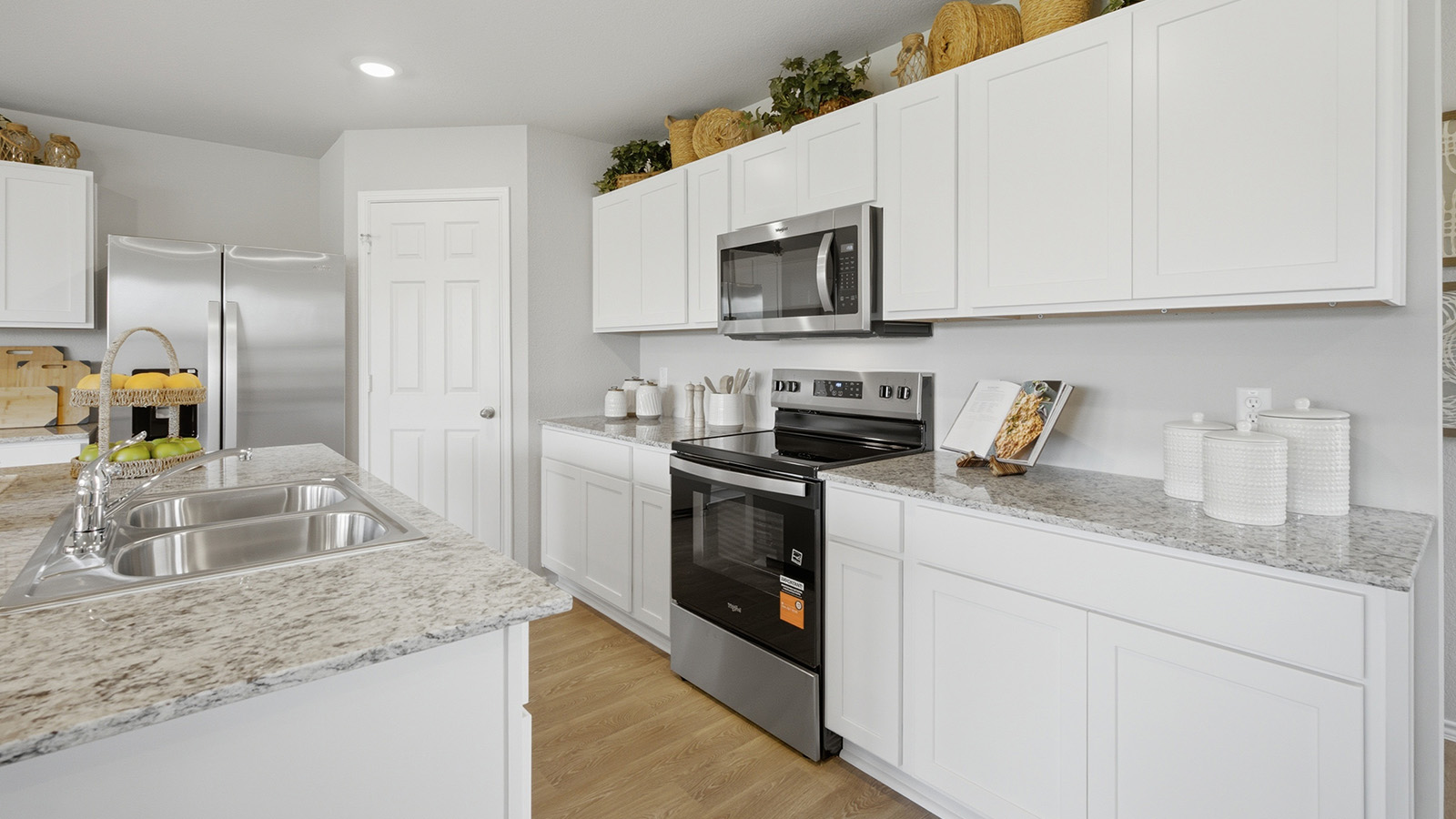 Cool Water model home kitchen with white cabinets and granite countertops.