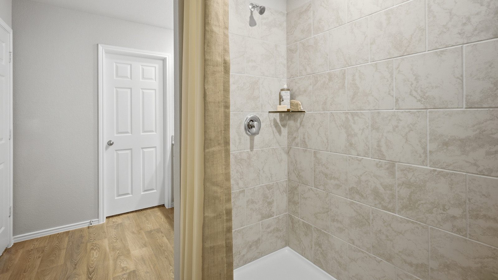 Cool Water model primary bathroom with walk-in shower and view of primary walk-in closet.