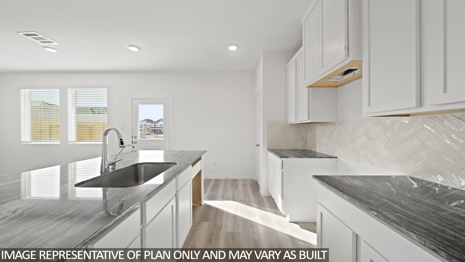 Gardenia kitchen with kitchen island and light cabinets and dark countertops with view of backdoor.