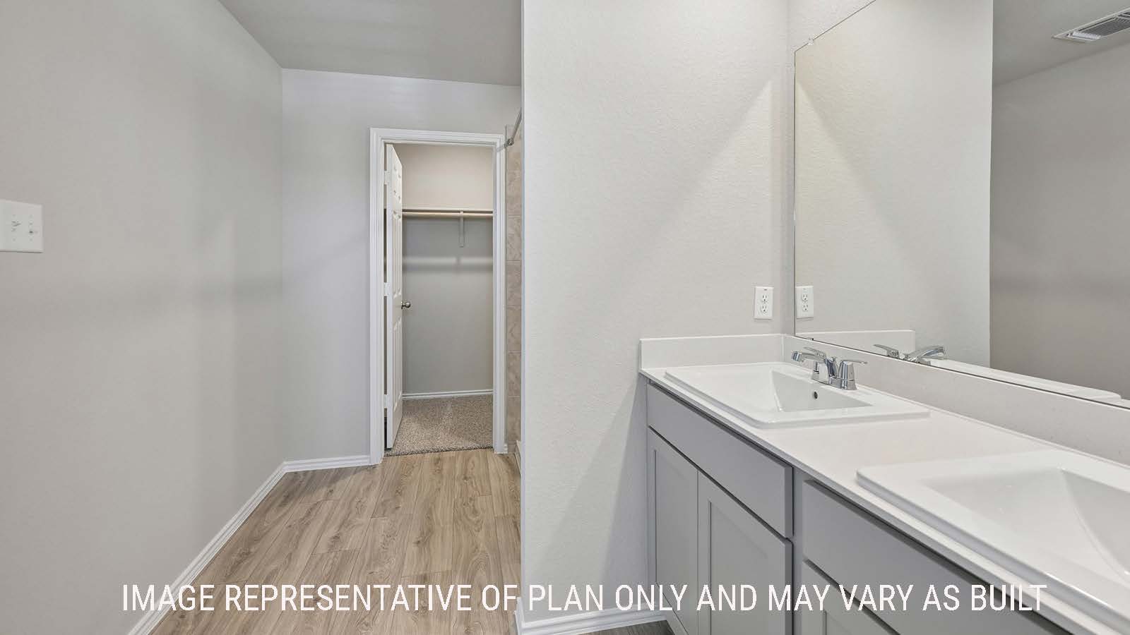 Gardenia primary bathroom with double vanity sink and view of primary bedroom walk-in closet.